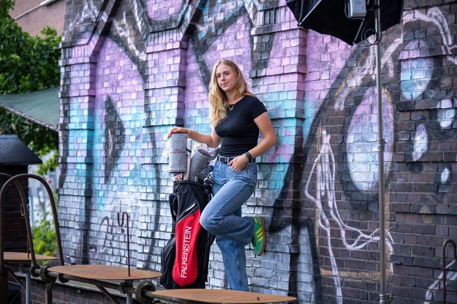 Leonie Wulfers mit Golfbag vor einer Graffitiwand